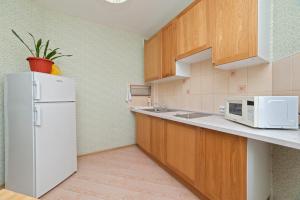 a kitchen with a white refrigerator and wooden cabinets at Apartments on Kuznechnaya 79 in Yekaterinburg