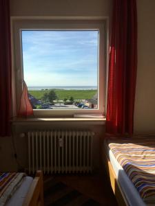 a bedroom with a window with a view of a parking lot at Apartment CAPTAIN'S LODGE in Norddeich