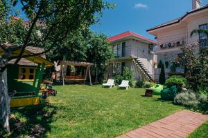 a yard with two white chairs and a house at Guest house VadLen in Odesa