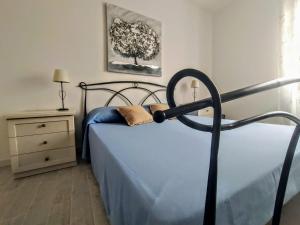 una camera da letto con un letto con lenzuola blu e un albero di Alghero Mare Chiaro-Guest House ad Alghero