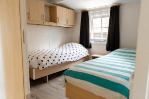 Un dormitorio pequeño con dos camas y una ventana. en Chalet aan de kust, en Sint Maartensvlotbrug