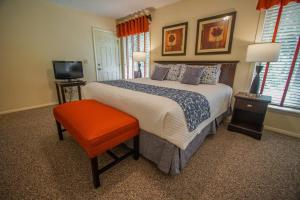 a bedroom with a bed with an orange stool and a television at Brewster Green Resort, a VRI resort in Brewster