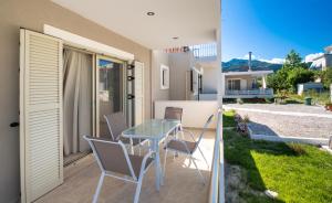 een patio met een glazen tafel en stoelen in een huis bij Bounatsa Studios & Apartments in Nydri