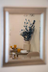 un miroir reflet d'une table avec un vase et des fleurs dans l'établissement Bounatsa Studios & Apartments, à Nydri