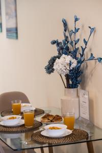 uma mesa de vidro com pratos de comida e um vaso de flores em Bounatsa Studios & Apartments em Nydri