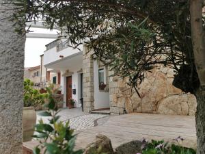 une maison avec un mur en pierre et une passerelle en bois dans l'établissement Bed & Breakfast Mare Isole, à La Maddalena