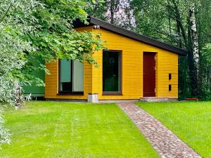 una casa amarilla con césped delante en Marijampole Camping, en Marijampolė