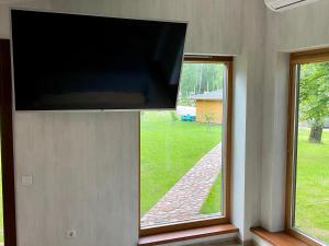 a flat screen tv hanging on a wall with two windows at Marijampole Camping in Marijampolė