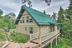 une cabine dans les bois avec un toit vert dans l'établissement Secluded Log Cabin with Game Room and Forest Views, à Red Feather Lakes