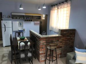 cocina con barra de ladrillo, mesa y sillas en Apto NOVO, totalmente equipado e bem localizado, en Bento Gonçalves