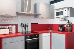 een rode en witte keuken met een fornuis en een magnetron bij Appartement Bastingage in Saint-Martin-de-Ré