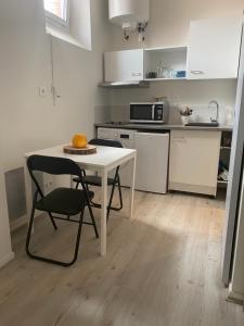 a small kitchen with a white table and a chair at Joli studio calme et lumineux in Royat