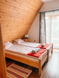 a bed in a room with a wooden ceiling at Urocze domki Zakopane in Zakopane