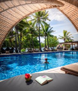 une femme dans une piscine avec une personne dans l'eau dans l'établissement Paradise Cove Resort, à Naukacuvu Island