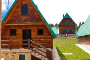 a log cabin with a green roof and two buildings at Vikendica Anja in Žabljak