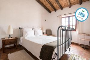 a white bedroom with a bed and a window at Horta da Quinta in Mértola