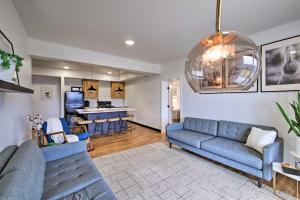 a living room with a blue couch and a kitchen at Luxe Amish Country Apartment with Rooftop Terrace! in Millersburg
