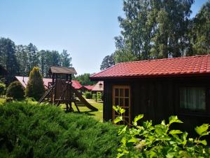 une petite cabine avec une aire de jeux à côté d'une maison dans l'établissement Viesu nams Vecmuiža, à Tūja