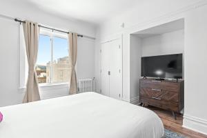 a white bedroom with a large bed and a flat screen tv at Kasa La Monarca San Francisco in San Francisco