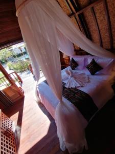 a bedroom with a bed with a mosquito net at Lumbung Bukit Resort Uluwatu in Uluwatu