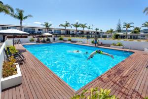 un hombre nadando en una piscina en un edificio en Palm Pacific Resort & Motel, en Whangamata