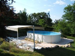 a pool on a deck with a canopy and chairs at Chambres d'Hôtes Domaine d'En Baleux in Labruguière