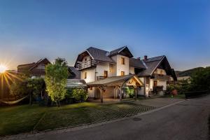 a large house with the sun setting behind it at Apartments Green Paradise in Bohinj