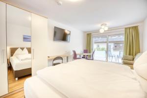 a hotel room with a large white bed and a living room at Ferienwohnungen Petschnig 1 in Drobollach am Faaker See