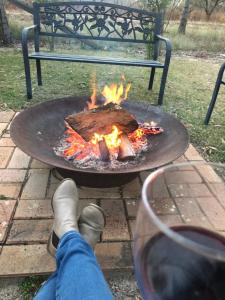 a person sitting on a bench with a fire burning in front of them at Briar Rose Cottages in Stanthorpe