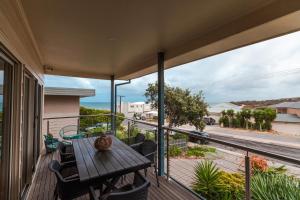 a balcony with a wooden table and chairs at Bella vista in Maslin Beach