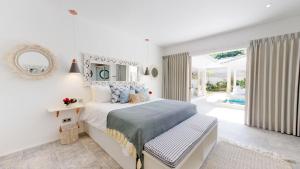 une chambre blanche avec un lit et une grande fenêtre dans l'établissement Sunyi Villas, à Kuta Lombok 115 autres photos