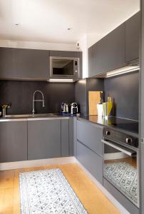 a kitchen with gray cabinets and a sink at Spacieux T2 remis à neuf, à 3 min des plages, terrasse in Anglet