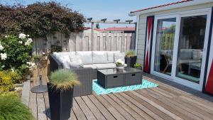 a patio with a couch and a table on a deck at Olmenduin Chalet Olm Zeeland in Serooskerke
