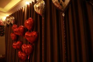 VES - PA Luxury Hotel في دالات: حفنة من بالونات القلب الأحمر أمام ستارة