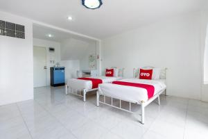 two beds in a white room with red and white sheets at OYO 908 Sabai Place in Hua Hin