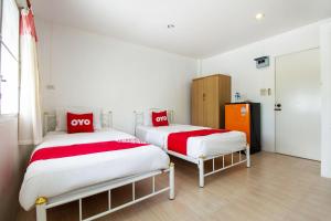 two beds with red and white sheets in a room at OYO 908 Sabai Place in Hua Hin