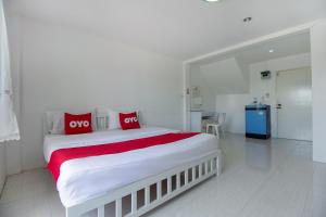 a white bedroom with a large bed with red pillows at OYO 908 Sabai Place in Hua Hin