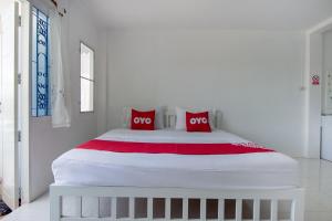a large white bed with two red pillows on it at OYO 908 Sabai Place in Hua Hin