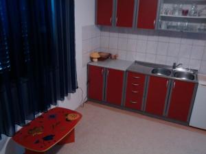 una pequeña cocina con armarios rojos y un taburete rojo en apartmani ANITA, Korčula, en Korčula