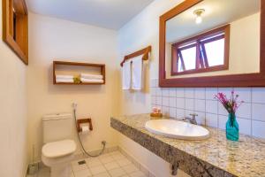 a bathroom with a sink and a toilet and a mirror at Charm Bahia Residencias in Arraial d'Ajuda
