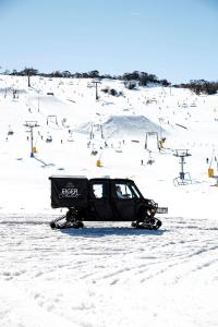 uma mota de neve estacionada na neve numa pista de esqui em Eiger Chalet em Perisher Valley