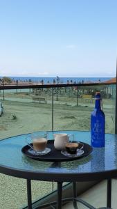 a table with two cups and a bottle on the beach at GP Apart SeaView, Mamaia Nord in Mamaia Sat/Năvodari