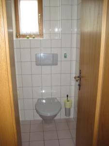 a bathroom with a toilet in a white tiled room at Machls Ferienwohnungen in Jerzens