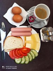 a plate of food with sausage and cheese and a cup of coffee at Отель "София" in Vinnytsya