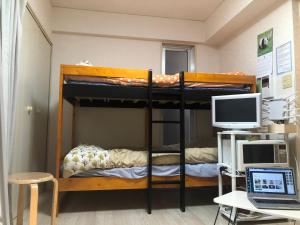een kamer met 2 stapelbedden, een computer en een bureau bij Cocone house Ohoripark in Fukuoka