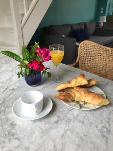 einen Tisch mit einem Teller Gebäck und einem Glas Orangensaft in der Unterkunft Deauville Triangle d OR in Deauville