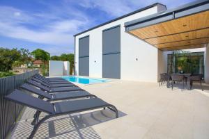 a patio with chaise lounges and a pool at Casa Bela in Klimno
