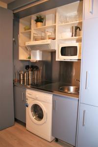 a kitchen with a washing machine and a microwave at Apartamentos Apartour Bormujos in Bormujos