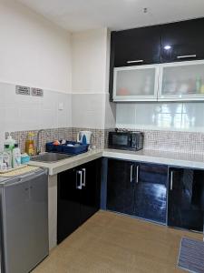 a kitchen with black and white cabinets and appliances at Ilham Homestay @ Anjung Vista Kubang Kerian in Kota Bharu
