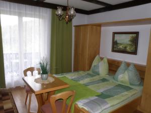 a bedroom with a bed with a table and a dining room at Gästehaus am Walde - Familie Troller in Ledenitzen